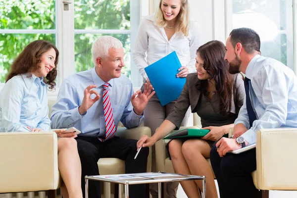 Vijf mensen uit het bedrijfsleven in de teamvergadering bestuderen van grafieken — Stockfoto