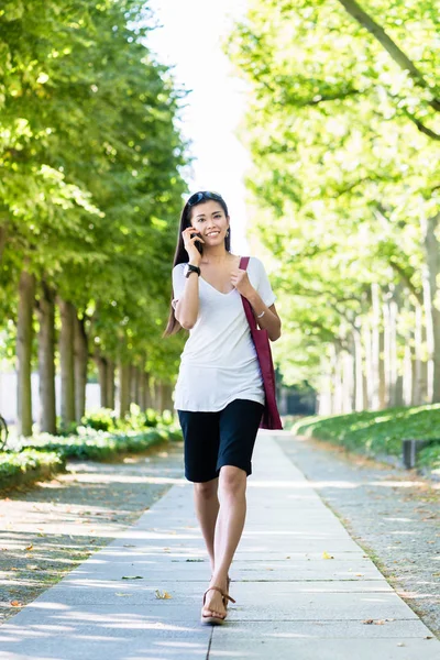 Азиатка разговаривает по мобильному телефону на улице — стоковое фото