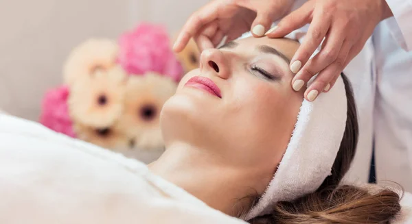 Hermosa mujer relajante durante el masaje facial rejuvenecedor en un — Foto de Stock