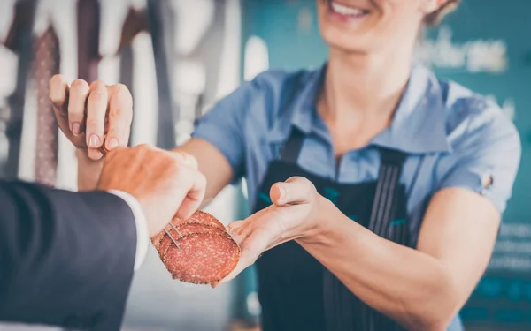 Trabajar en una carnicería - asistente de tienda entregando carne a cust —  Fotos de Stock
