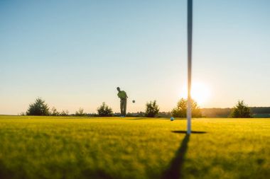 oyuncu golf sahasında topa vuruyor