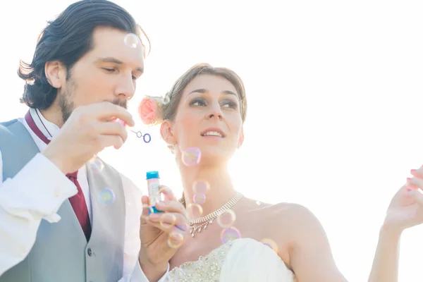 Svatební pár vyfukuje bubliny — Stock fotografie