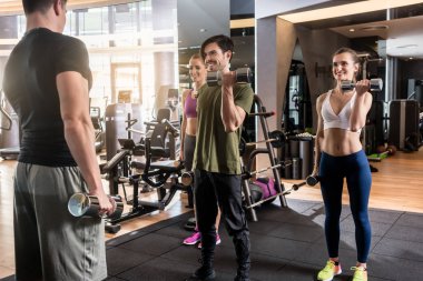Dumbbell pazı kıvırmak alternatif gülümseyen üç gençler