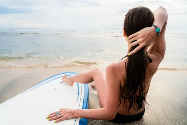 Female surfer sitting next to Board after Surfing at beach — Stock Photo, Image