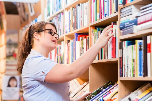 Жінка в книгарні шукає книгу — стокове фото