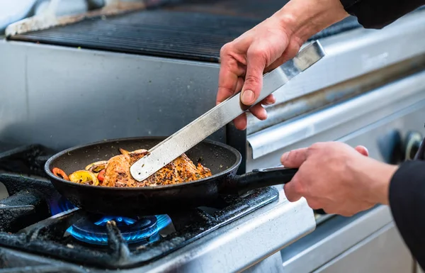 Koch dreht beim Kochen Fisch in Pfanne — Stockfoto