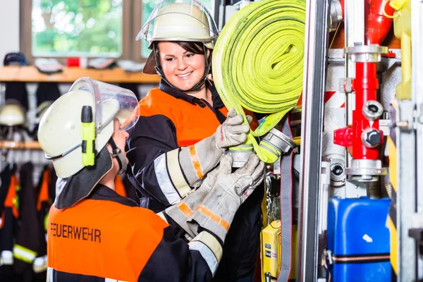 Bombeiros que carregam mangueiras no veículo de operações — Fotografia de Stock