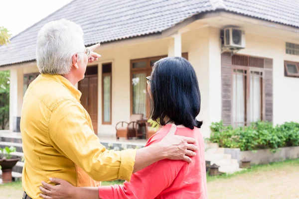 Elderly man pointing to a comfortable residential house while st — Stock Photo, Image