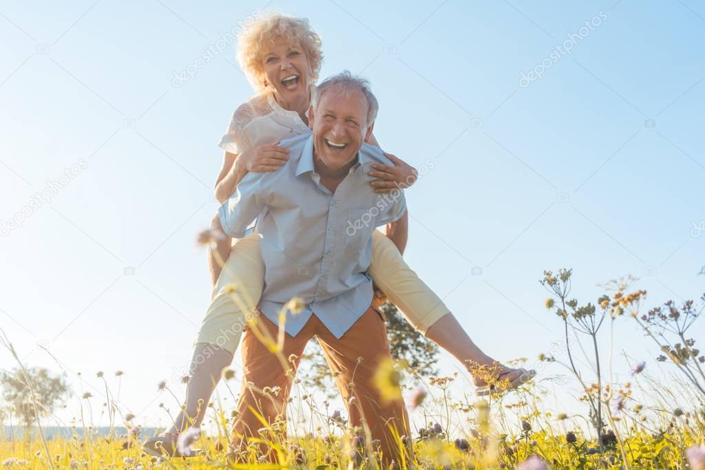 Happy senior man laughing while carrying his partner on his back