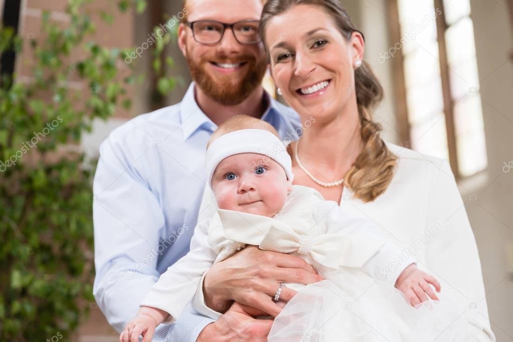 Parents kissing baby at christening