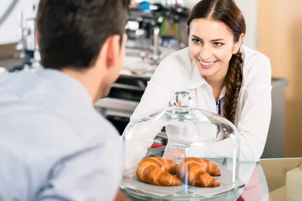 Amistosa camarera señalando croissants franceses en el café sh — Foto de Stock