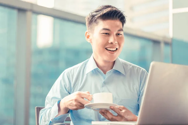 Homme d'affaires chinois prenant un café à son ordinateur portable assis devant — Photo