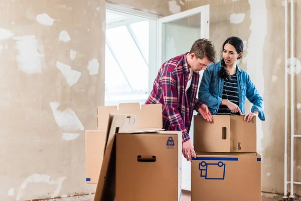 Jong koppel dozen openen tijdens renovatie van nieuw huis na m — Stockfoto