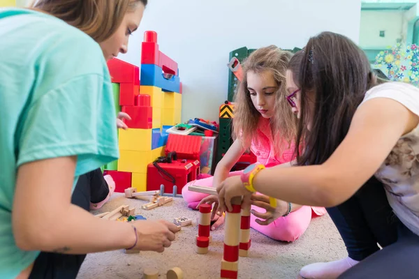 Girls playing together with wooden toy blocks on the floor durin — Stock Photo, Image