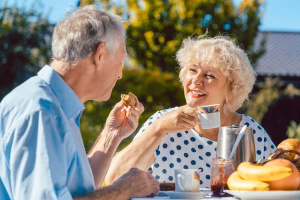 Feliz pareja de ancianos desayunando en su jardín al aire libre i — Foto de Stock