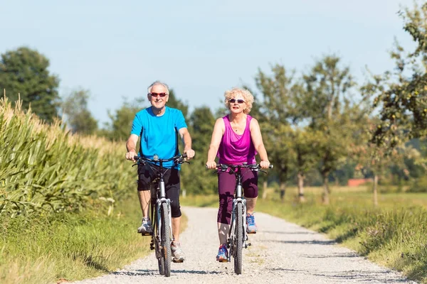 Active senior couple enjoying retirement while riding bicycles i — Stock Photo, Image