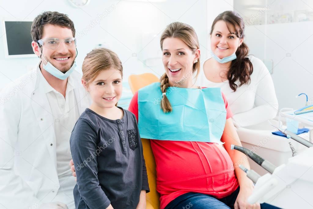 Dentist with pregnant woman and child in surgery