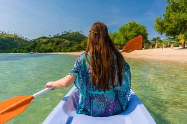 Genç kadın bir pastoral adalar kıyısında kano kürek çekmeye