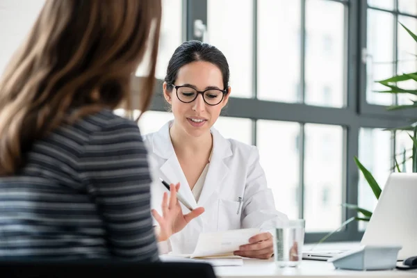 Female physician listening to her patient during consultation in — Stock Photo, Image