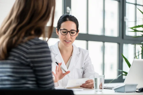 Médico femenino escuchando a su paciente durante la consulta en —  Fotos de Stock