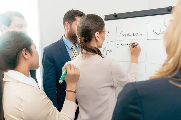 Directora ejecutiva escribiendo en un tablero de papel lo positivo — Foto de Stock