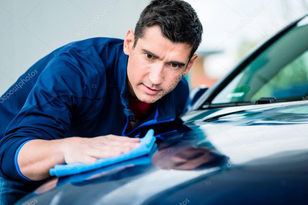 Young man polishing blue car
