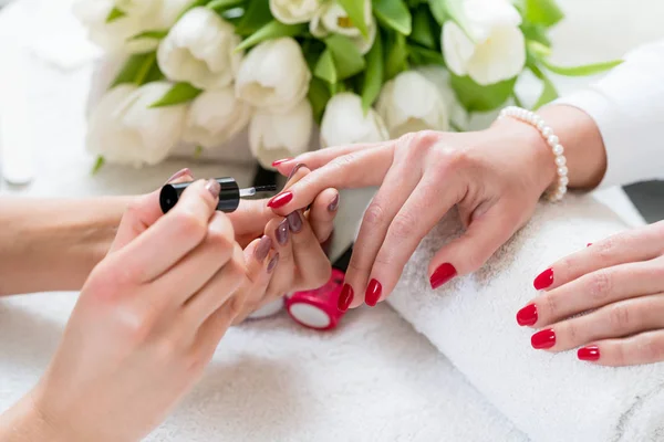 Handen van een ervaren manicure toepassing van rode nagel Pools op de waarde n.v.t. — Stockfoto