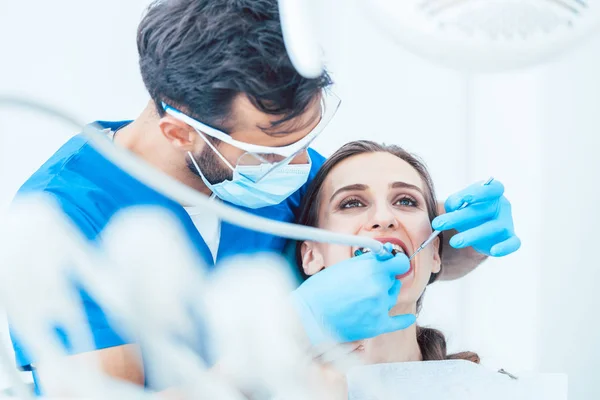 Jonge vrouw tijdens pijnloos mondelinge behandeling in de moderne tandheelkundige kliniek — Stockfoto