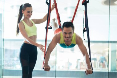 Egzersiz dersi ile uçan yoga uygulamak süre asılı neşeli genç adam 