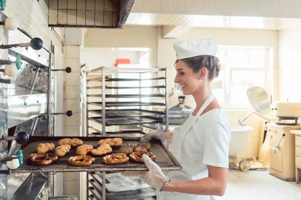 Baker vrouw krijgen van bakkerijproducten uit oven — Stockfoto