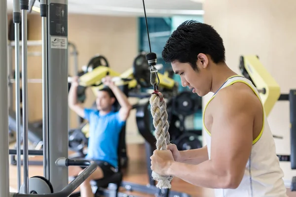 Fuerte joven ejercitando tríceps empujar hacia abajo en el cable de la cuerda m — Foto de Stock