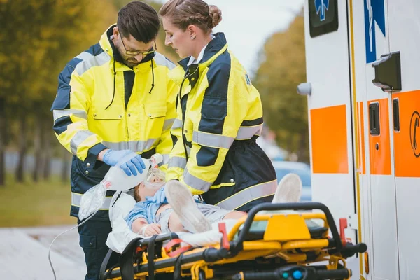 Médicos de emergência que dão oxigénio à vítima — Fotografia de Stock
