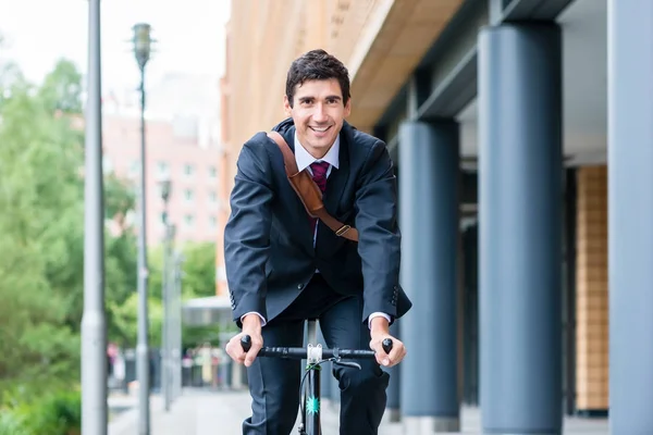 Homem andando de bicicleta perto de edifícios de escritórios — Fotografia de Stock
