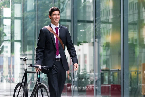 Человек ходит на велосипеде рядом с офисными зданиями — стоковое фото