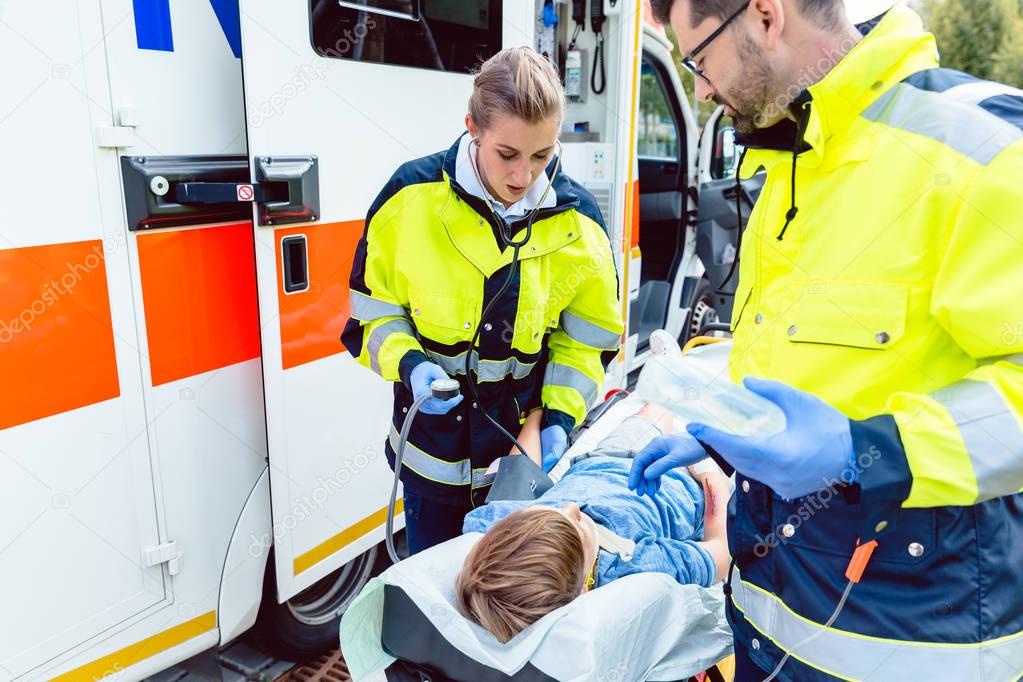 Paramedics measuring blood pressure of injured boy