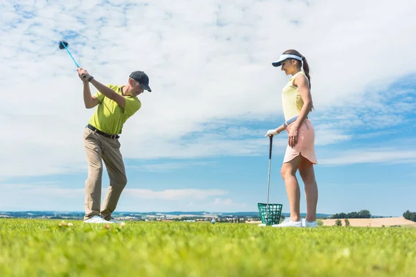 Mujer joven practicando el movimiento correcto durante la clase de golf con un — Foto de Stock