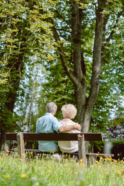 Romantic elderly couple sitting together on a bench in a tranqui — Stock Photo, Image