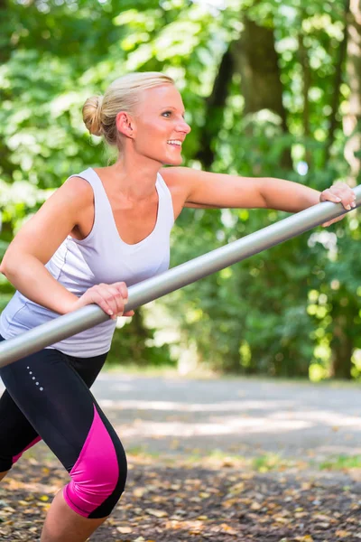 Νεαρή γυναίκα stretching πριν από το άθλημα στο μονοπάτι άθλησης — Φωτογραφία Αρχείου