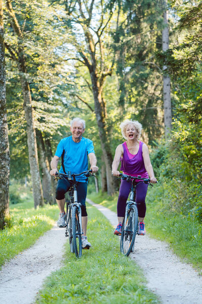 Счастливая и активная пожилая пара на велосипедах на свежем воздухе в р
