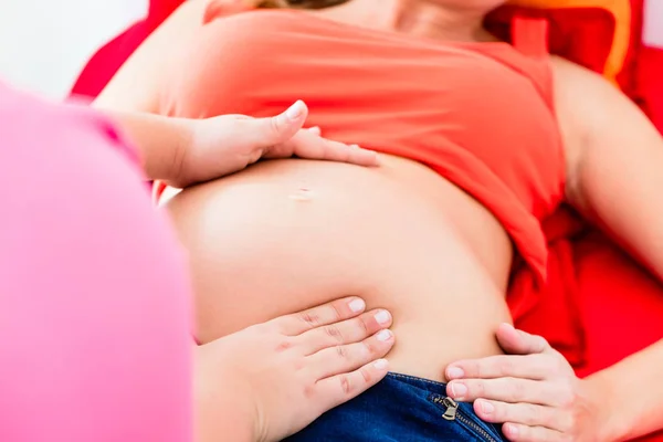 Акушерка эксанимирует живот беременной женщины вручную — стоковое фото