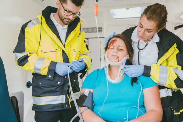 Bakımı sağlık görevlilerinin kadın ambulans içinde inured. — Stok fotoğraf