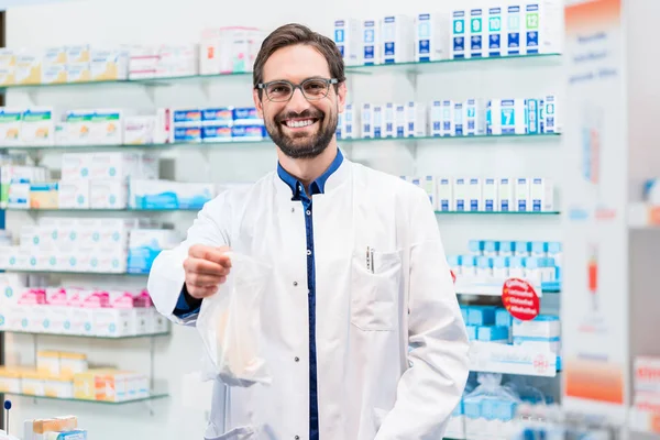 Farmacéutico en farmacia que vende productos farmacéuticos en bolsa —  Fotos de Stock