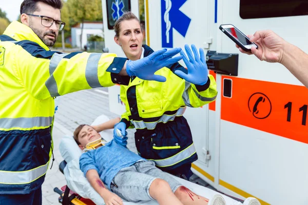 Ambulanspersonal kämpar människor som försöker göra bilder av olycka — Stockfoto