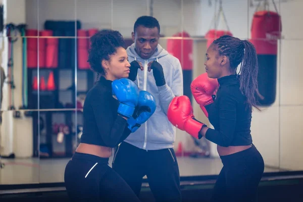 Entrenador de boxeo experimentado supervisando y enseñando a dos mujeres b —  Fotos de Stock