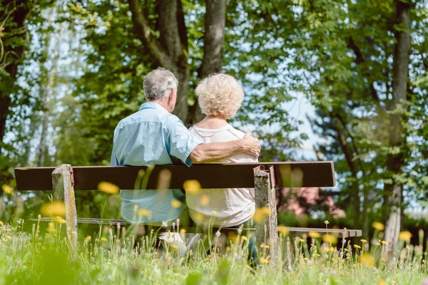 Casal de idosos românticos sentados juntos em um banco em um tranqui — Fotografia de Stock