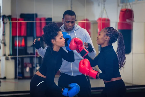 Entrenador de boxeo experimentado supervisando y enseñando a dos mujeres b —  Fotos de Stock