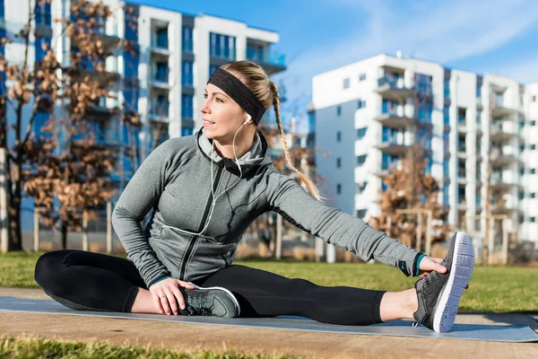 Vältränad ung kvinna stretching hennes ben under utomhus warm-up var — Stockfoto