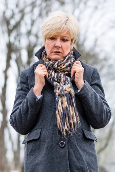 Depressed woman walking in winter garden — Stock Photo, Image