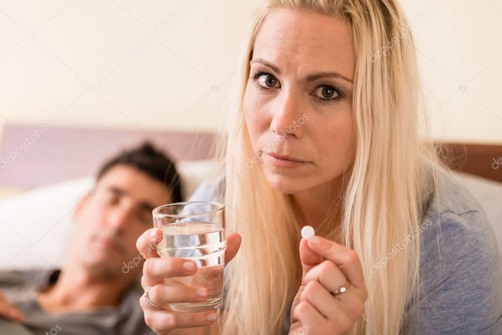 Worried woman taking a pill before sleep at night