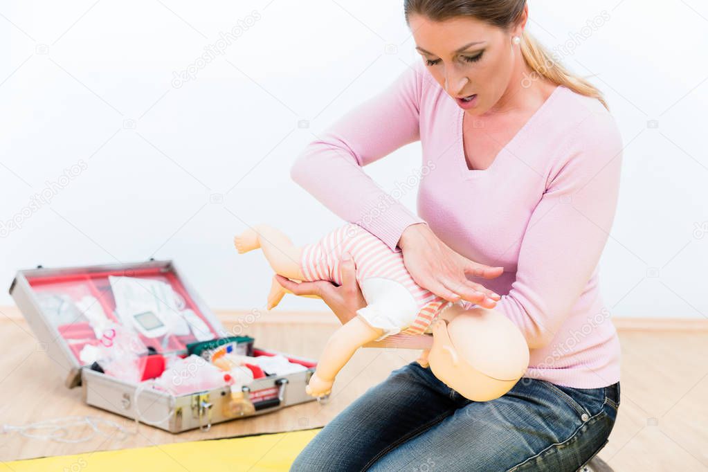 Woman in first aid course practicing revival of infant on baby d